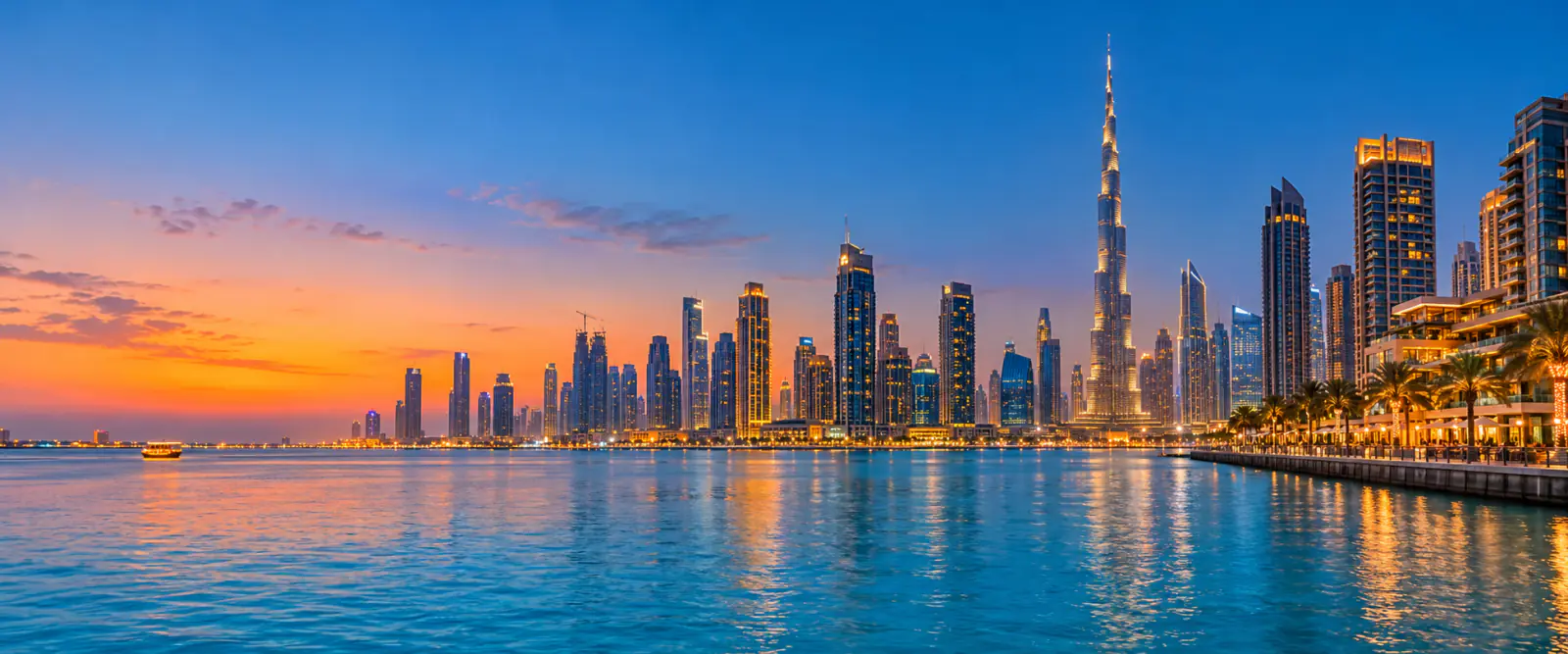 Dubai waterfront skyline reflected in blue water at sunset.